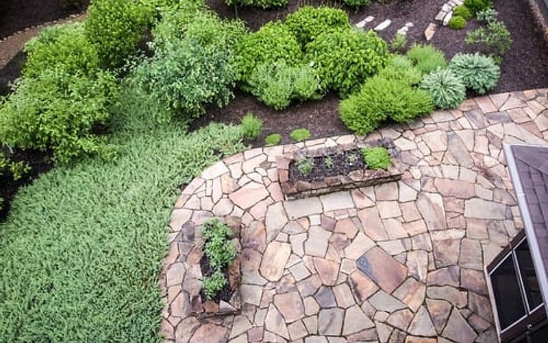 Manicured Hamptons estate grounds with stone patio and planted borders maintained by All 4 Seasons Property Care